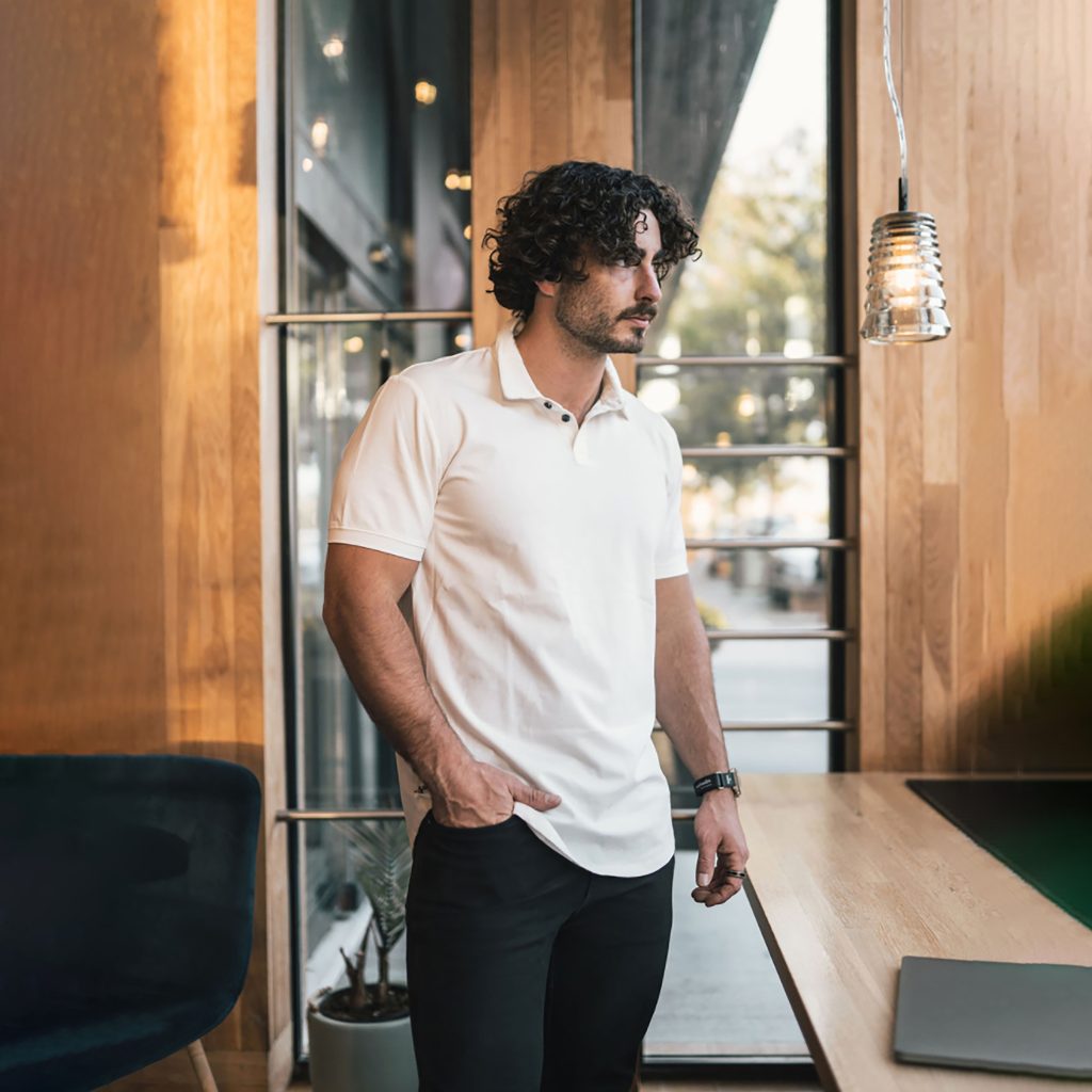 Male model standing with black chino pants on. From the office, to golf the Stratus Polo from ten10 apparel is the best performance polos for men