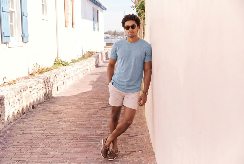 Man in Curved Hem Drop Cut light blue tee from the brand ten10 apparel with khaki colored shorts on a European street
