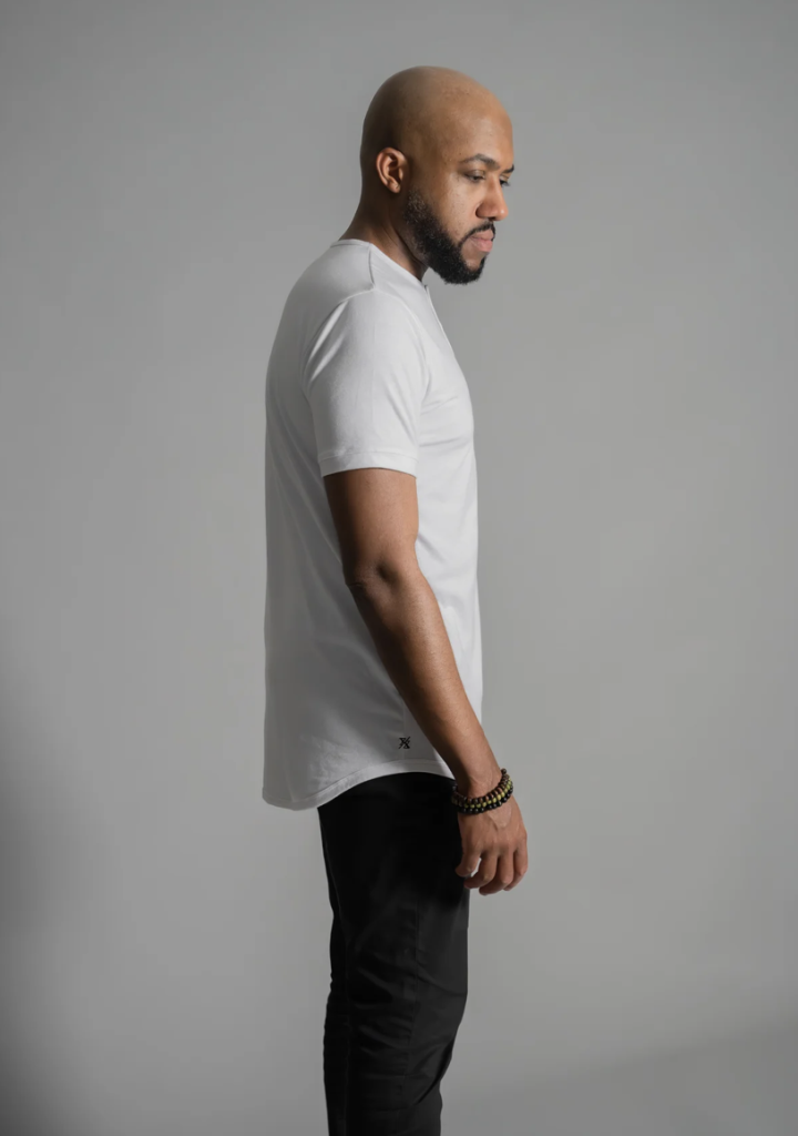 man in white short sleeve curved hem henley standing dramatically