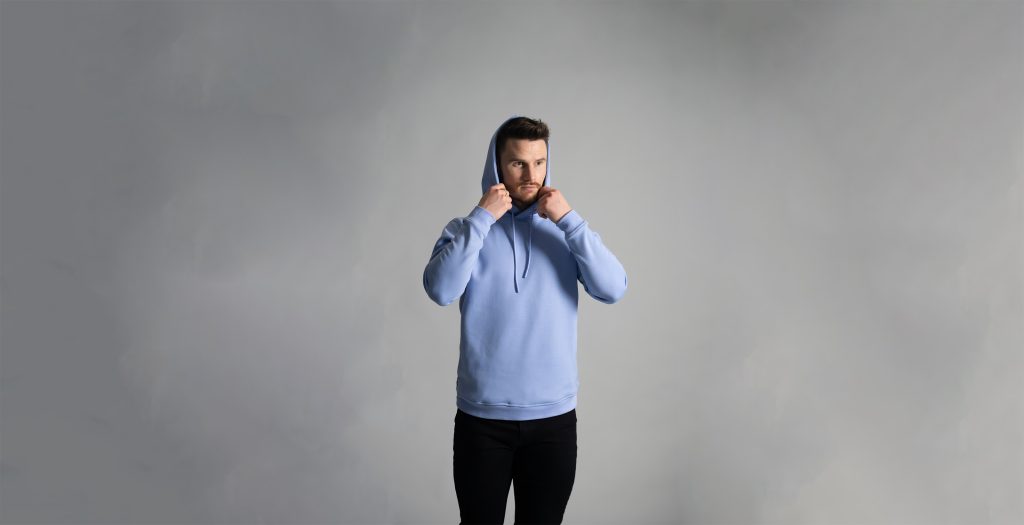 Man putting on blue Mist Cortex Hoodie from ten10 apparel