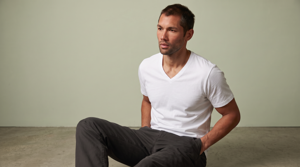 man in a white v-neck tee sitting down